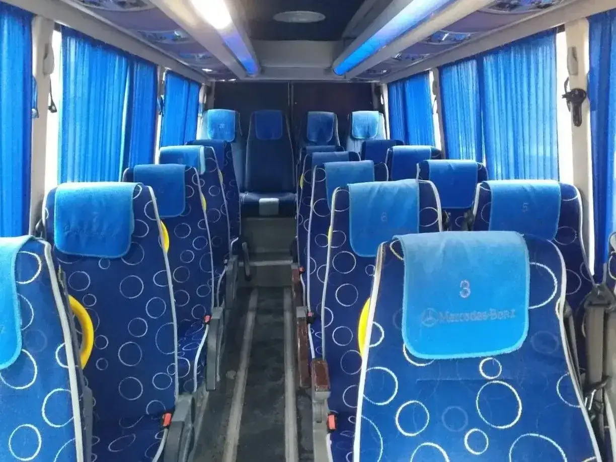 Wygodne siedzenia w autobusie, idealne na podróż z Tirany do Durrës. Błękitne zasłony i wzorzyste obicia dodają uroku.