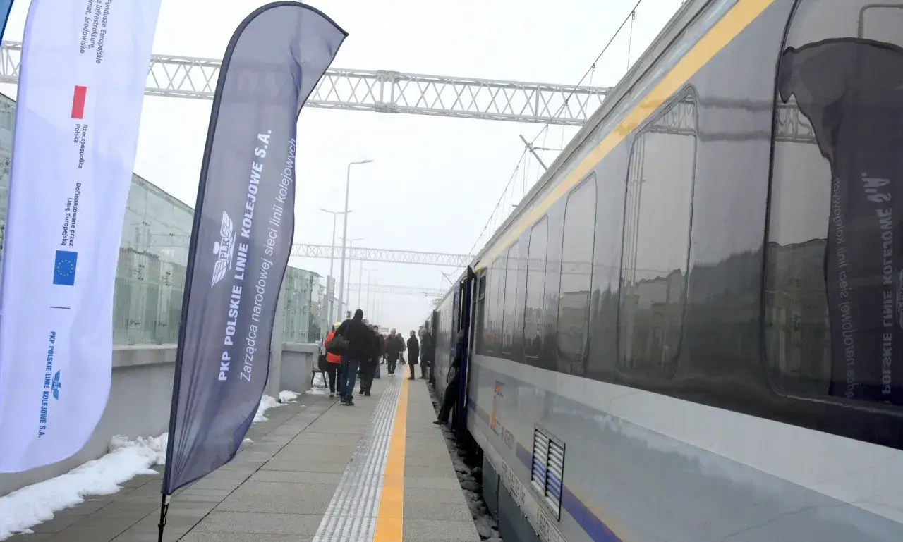 Pociąg PKP na peronie, obok flagi z napisem 