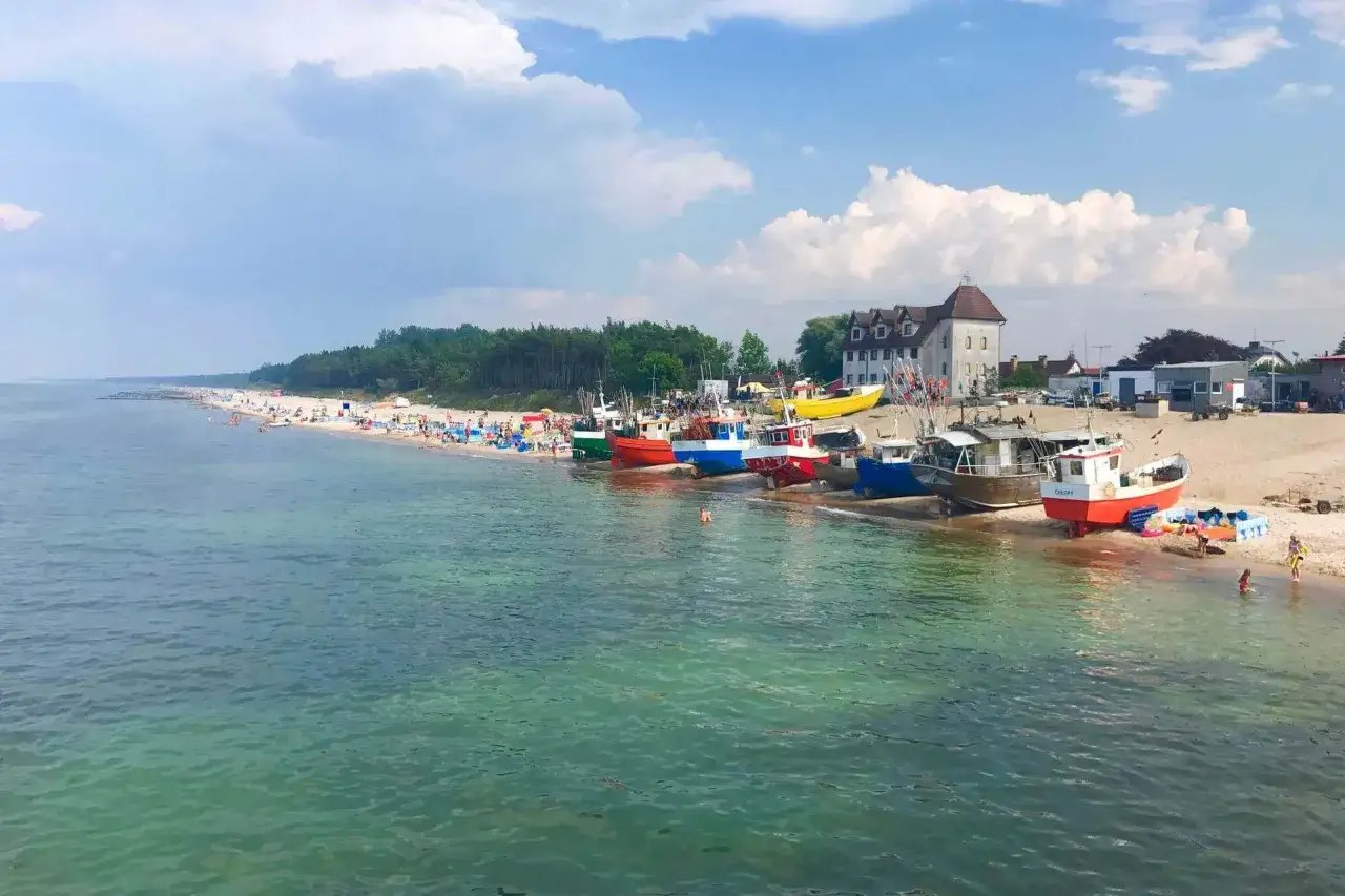 Kolorowe łodzie rybackie na plaży w Chłopach, obok wypoczywających ludzi. Idealne chłopy atrakcje dla każdego.