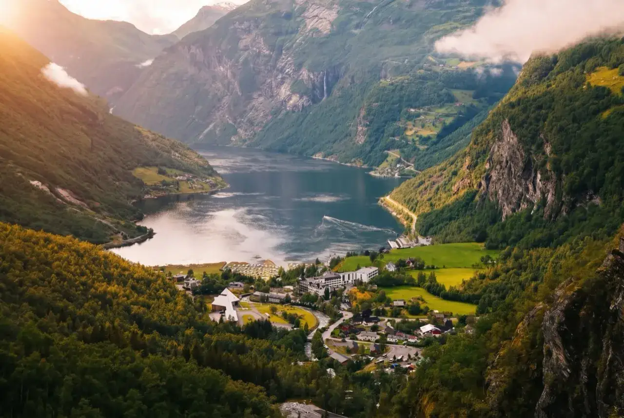 Piękna Norwegia w czerwcu, z łagodną pogodą, ukazuje malowniczy fiord otoczony zielonymi wzgórzami i górami.