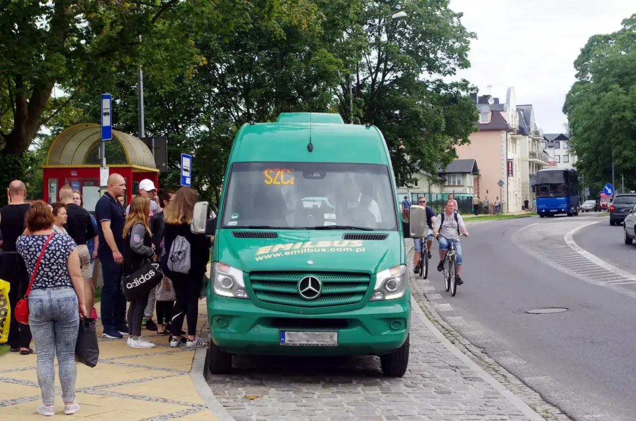 Zielony bus Emilbus czeka na pasażerów na przystanku w Międzyzdrojach, gotowy do kursu do Dziwnowa.