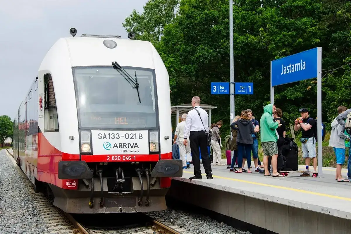 Pociąg Arriva z napisem HEL na wyświetlaczu stoi na stacji Jastarnia. Pasażerowie czekają na peronie, gotowi do podróży z Helu.