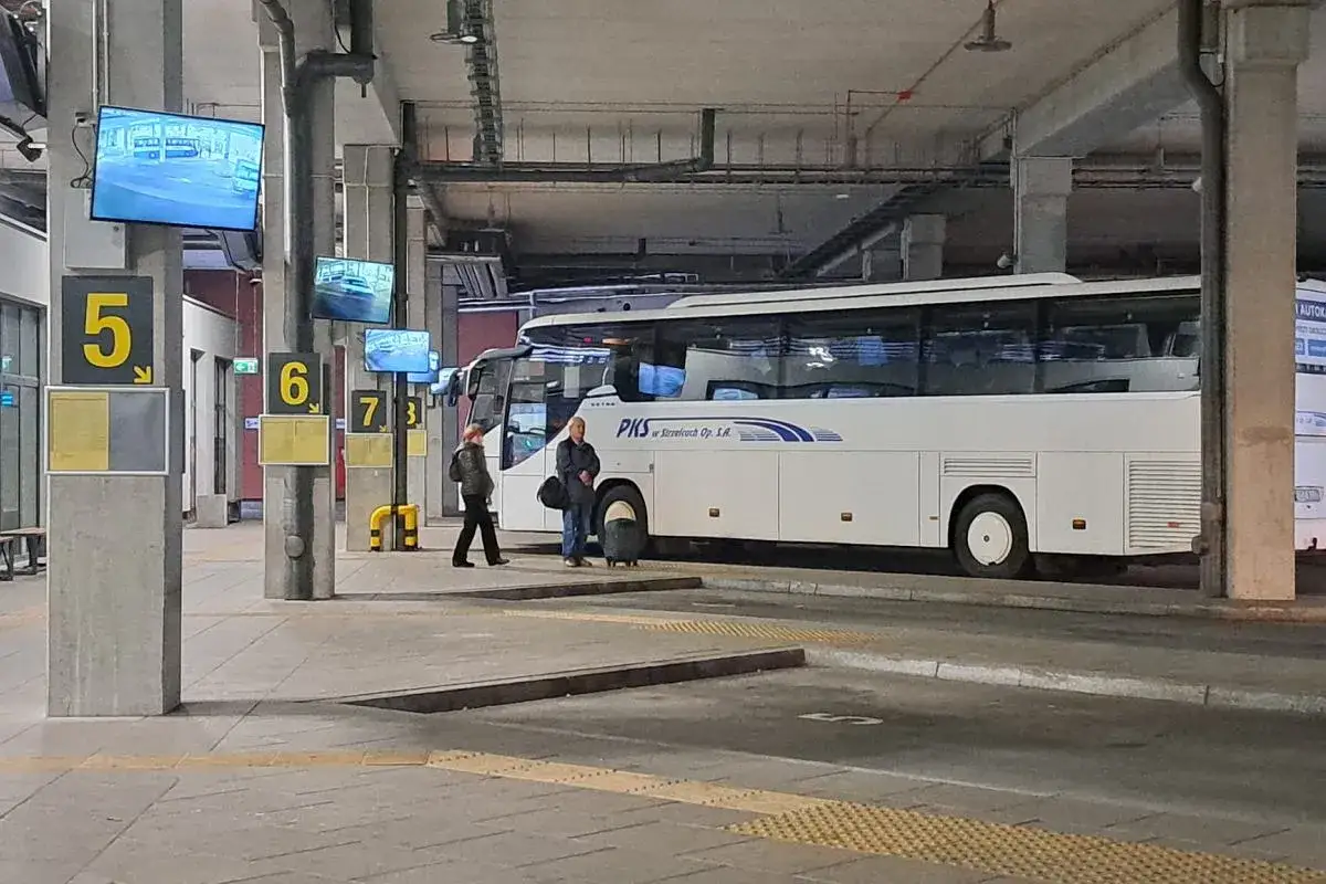 Oczekujący na autobus PKS w Grodźcu. Dwa autokary stoją na stanowiskach 5 i 6.