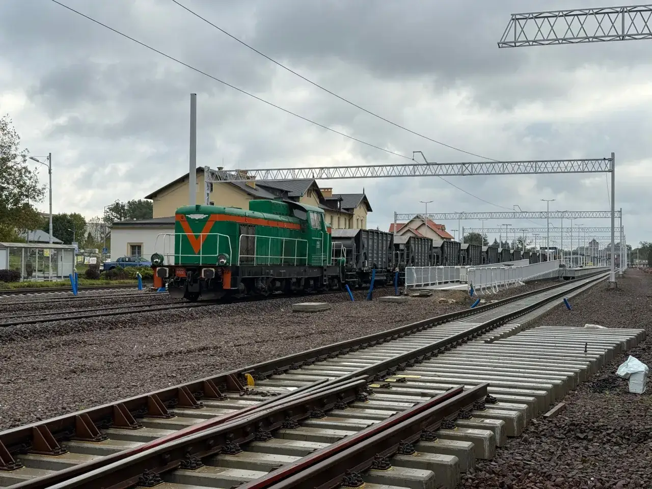 Zielona lokomotywa z wagonami towarowymi na torach. Szukasz informacji o express bus Kętrzyn Olsztyn cena?