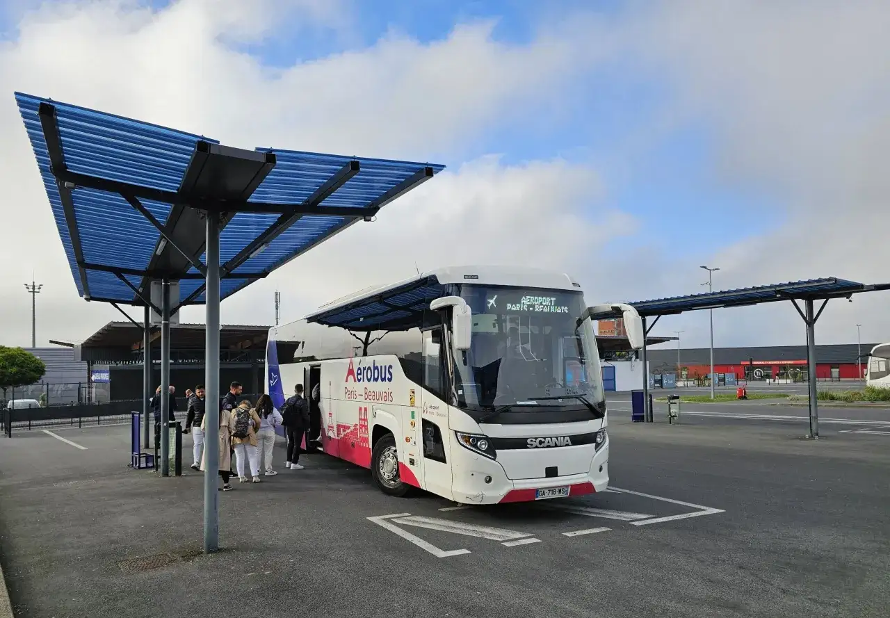 Autobus Aerobus Paris-Beauvais czeka na pasażerów pod niebieskim zadaszeniem.