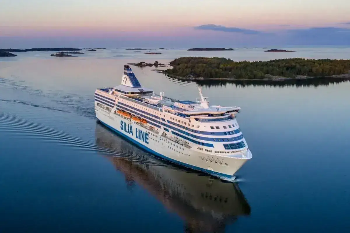 Prom Tallin Helsinki cena: duży statek Silja Line płynie przez spokojne morze wśród wysp o zachodzie słońca.