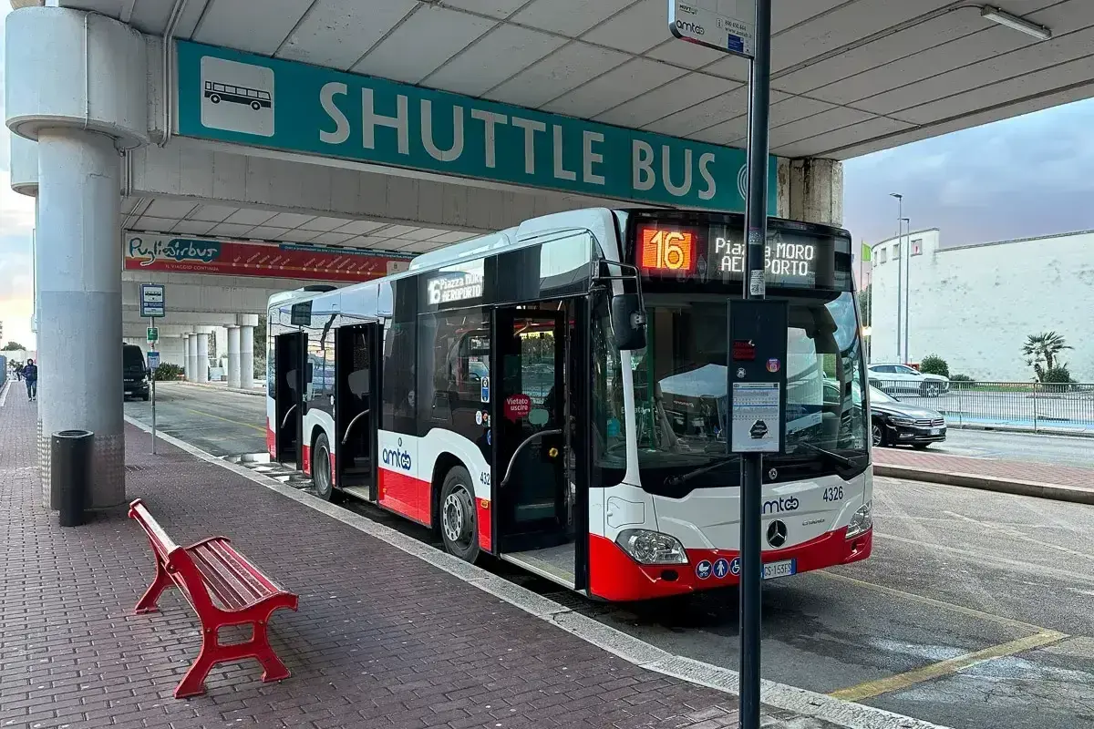 Autobus wahadłowy na lotnisko Bari. Czerwona ławka czeka na pasażerów pod znakiem
