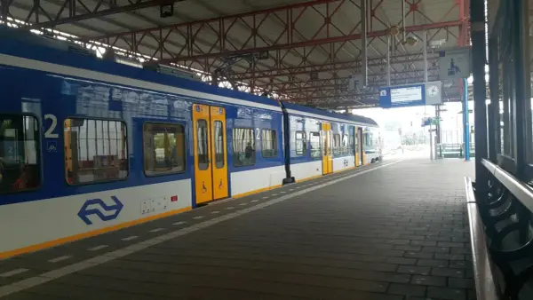 Niebiesko-biały pociąg na stacji, gotowy do podróży z Eindhoven do Amsterdamu.